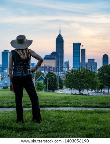 Woman with a hat watching sunset over Indianapolis skyline