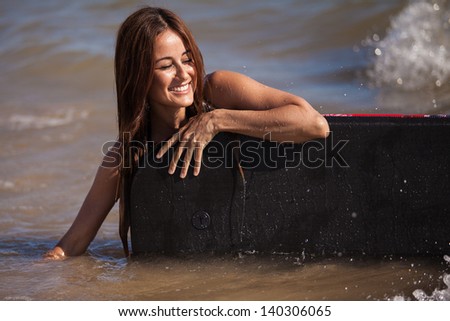 Happy girl having fun with a body board at the beach