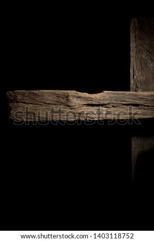 Old rotten logs stacked in crossbeams on a black background
