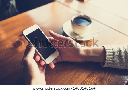 Woman using smartphone on wooden table in cafe. Close-up image with social networks concept