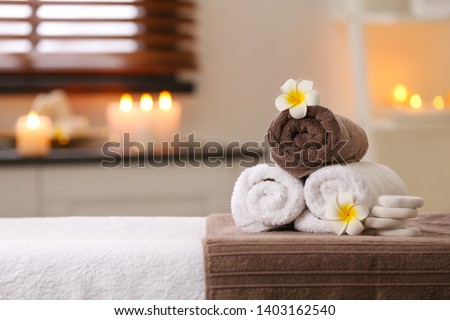 Composition with towels, flowers and stones on massage table in spa salon. Space for text Royalty-Free Stock Photo #1403162540