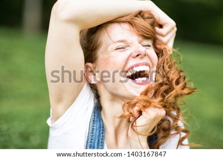 Young beautiful redhead woman with blue eyes and freckles in nature is having fun and relaxing