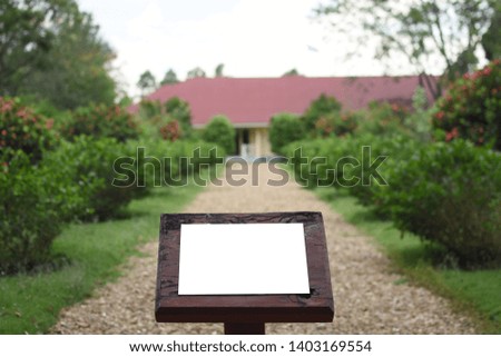 White isolated sign on wooden base in front of pathway to big house, space for sale or advertisement text