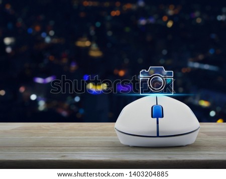 Camera flat icon with wireless computer mouse on wooden table over blur colorful night light city tower and skyscraper, Business camera shop online concept