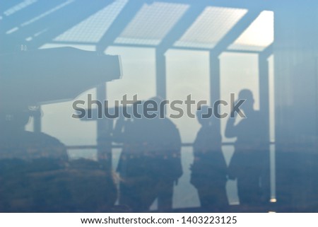 Silhouette of a people watching through telescope on observation tower; Landscape is visible in the background