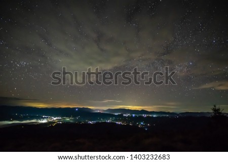 Starry sky over the mountain city in the fog