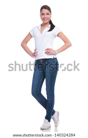 full length picture of a casual young woman standing with her hands on her hips and smiling to the camera. isolated on white background