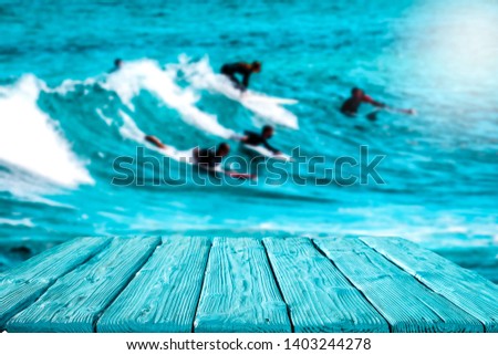 Blue wooden table of free space for your decoration and surfers on waves. 