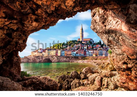 Unusual view with old clock towe in Piran through a rock hole. the tourist center of Slovenia. popular tourist attraction. Wonderful exciting places.  Royalty-Free Stock Photo #1403246750
