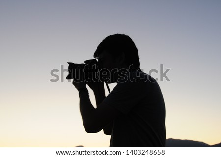 Silhouette of female taking photo