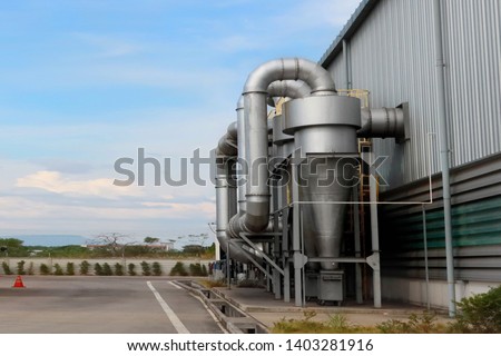 Air pollution control equipment as dust cyclone collection and chimney stack locates out of industrial building. Royalty-Free Stock Photo #1403281916