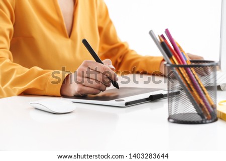 Cropped photo of european young designer woman using graphic tablet computer and stylus pen while working in bright office