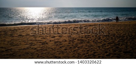 Wide shot of sun-setting beach. The beach is full of footprint but the photo feels lonely, calm and warm.