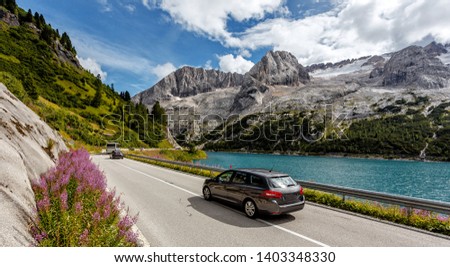 Awesome alpine highland in sunny day. Colorful spring scene. Summer view of Asphalt road near Fedaia lake and Marmolada mountain.  Amazing natural scenery in Dolomites Alps. Picture of wild area