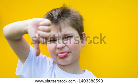 cute boy showing blurred thumb down. focus on face. child showing his tongue. childhood, expressions and school concept