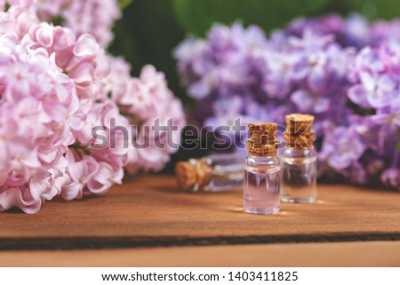 essential oil bottles and lilac blossoms on wooden table