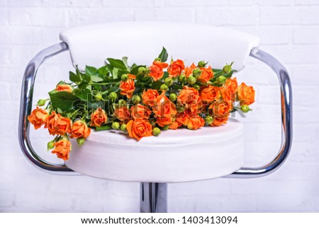 Bouquet of orange roses on a chair close-up. Beautiful bouquet on a white background.