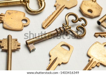 Lot of keys old and new yellow gold color on a white background.