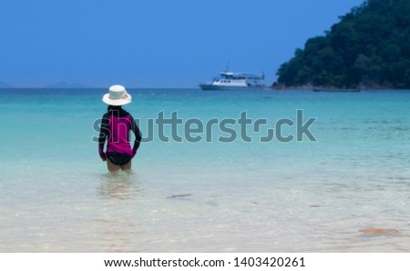 back side view of girl stand in sea during summer vacation on tropical beach and with blurred background