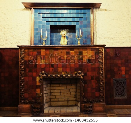 fireplace covered in bardic and blue tiles with candlesticks and clocks