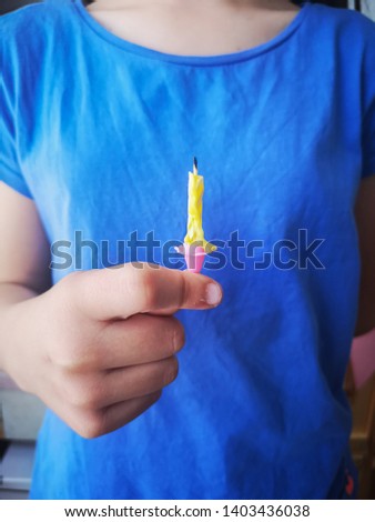 little girl hand holding a yellow spiral birthday candles off