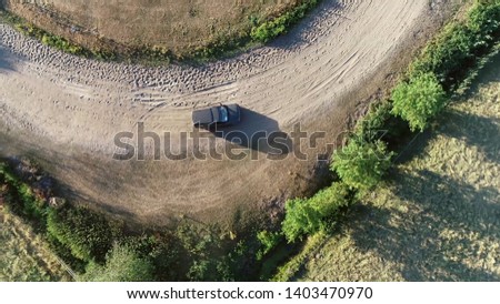 Aerial top down photo of sport utility vehicle SUV driving over off-road gravel surface advanced vehicle equipped with raised ground clearance and four-wheel drive to support countryside unpaved roads Royalty-Free Stock Photo #1403470970