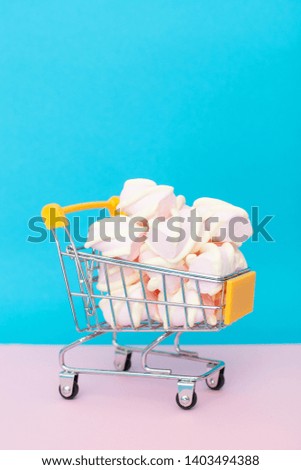 sweet and tasty pastry - marshmallow, in the basket for products, shopping cart on a pink-blue background with space for text. vertical frame