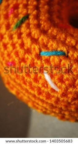Knitted orange donut with dressing on the background of boxes close-up. Handmade for children playing in a store or cafe.