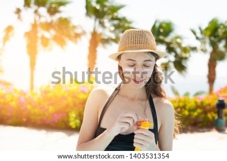 beautiful woman smears face sunscreen at the beach for sun protection