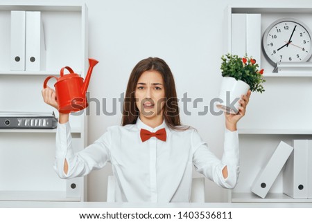 Business woman sitting at a desk and holding a flower with a pot office