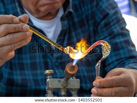 Men glassblower make handmade products  under gas burner.