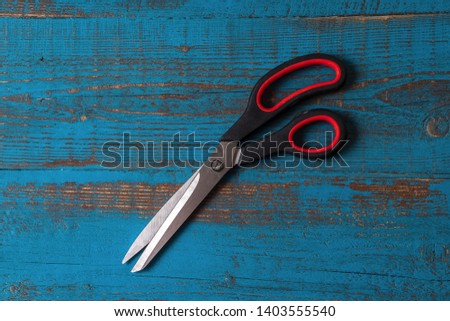 Flat lay A pair of used ckitchen scissors against old blue wooden background.
