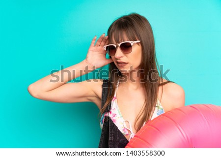 Young woman in bikini over blue wall unhappy and frustrated with something. Negative facial expression