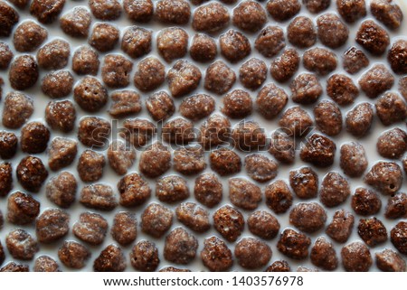 A picture of the background with brown chocolate corn balls for breakfast in a plate with milk.