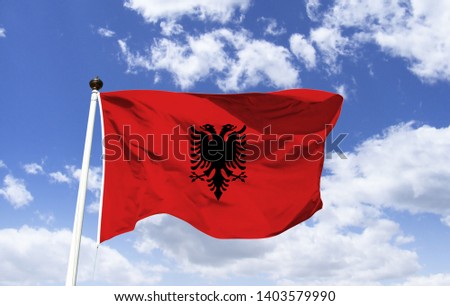 Albania flag mockup fluttering under blue sky. It is red with a double-headed black eagle, derived from the coat of arms, the highest symbol of the country's official representation.