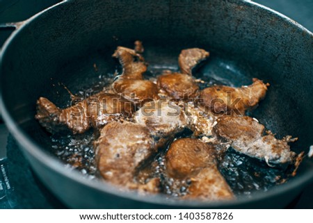 fish been fried on bowling oil inside an iro pan, seen from a side