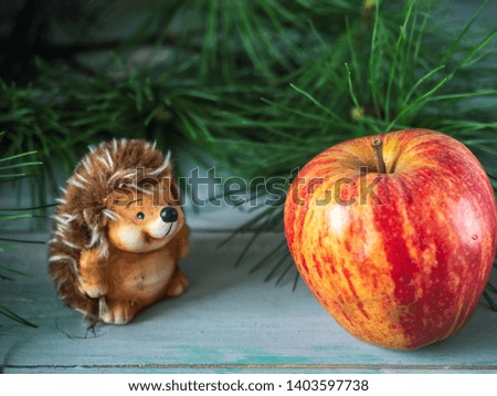 Christmas picture on a blue wooden background, a hedgehog toy found a big red apple