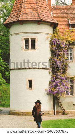 Woman walking in city park relaxing on weekend. Person enjoying old castle view. Spring lifestyle activity, people outside. Sun getaway Caucasian woman in hat with camera - Image