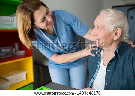 Happy caretaker assisting senior man. Friendly nurse supporting old man with Parkinson's Disease Royalty-Free Stock Photo #1403646170