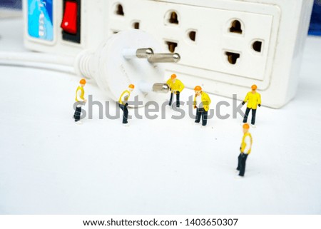 miniature electronic technician working to connect electricity. figurine concept of industry working.