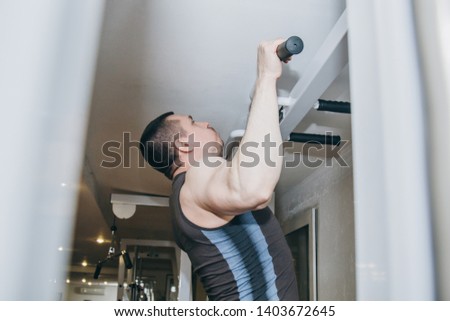 athlete trains the back muscles in the center of training. pull-ups on the horizontal bar in the gym.