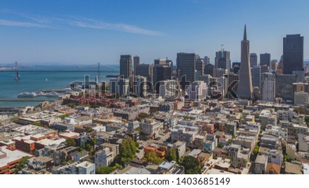 Skyline of downtown San Francisco over houses, with Oakland Bay Bridge over water, viewed from Coit Tower, in San Francisco, USA