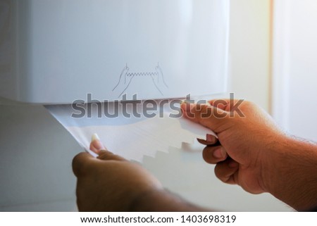 Men's hand pulling toilet paper, toilet paper in box.Paper towel dispenser Royalty-Free Stock Photo #1403698319
