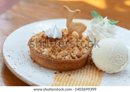 Classic crispy apple crumble with vanilla ice cream fresh whip cream and animal biscuit in beautiful plate.  Pastries crispy desert.