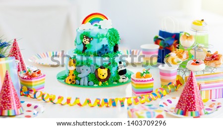 Cake for kids birthday celebration. Jungle animals theme children party. Decorated room for boy or girl kid birthday. Table setting with presents, gift boxes, confetti and sweets. Pastry for child Royalty-Free Stock Photo #1403709296