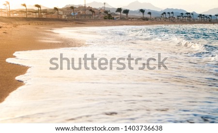 Closeup image of beautiful blue ocean waves rolling on the sandy sea beach against amazing sunset