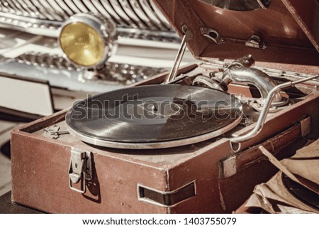 Vintage vinyl record player by the retro car.