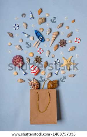 Various decorative nautical items, seashells, sea stars and miniature toys flying from kraft paper bag on blue pastel background. Sea travel, summer vacation at ocean concept. Flat lay, top view