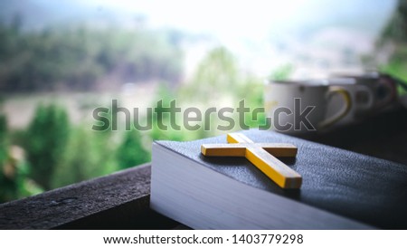 Yellow cross on the Bible in morning with coffee cup background. christian symbol concept.