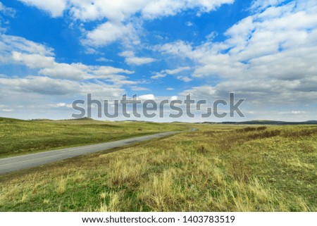 Picturesque steppe landscape.  Blue sky, grass, road. Burabay National Nature Park in Republic of Kazakhstan. Spring time. Travel to central Asia. May, 2019.